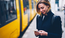 Personne sur son téléphone avec un tramway à côté