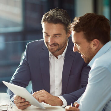 Deux hommes en costume lisant un document, symbolisant la préparation d'un audit