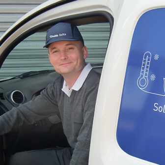 Collaborateur Chubb Delta assis dans un véhicule professionnel, casquette Chubb Delta, porte ouverte, prêt à intervenir