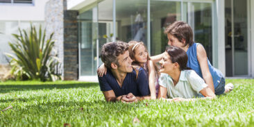 Famille qui est allongée dans l'herbe devant un bâtiment