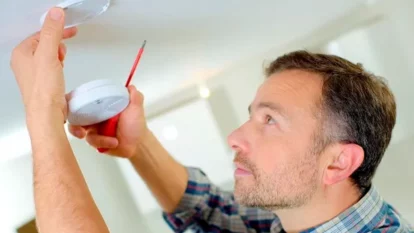 man-adjusting-smoke-detector